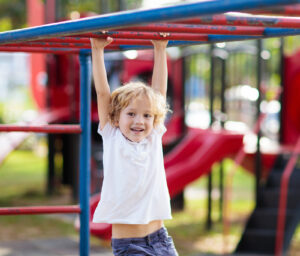 Child playing on outdoor playground. Kids play on school or kindergarten yard. Active kid on colorful monkey bars. Healthy summer activity for children. Little boy climbing.
